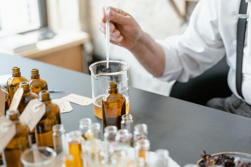 A person blends essential oils in glass bottles for aromatherapy indoors.